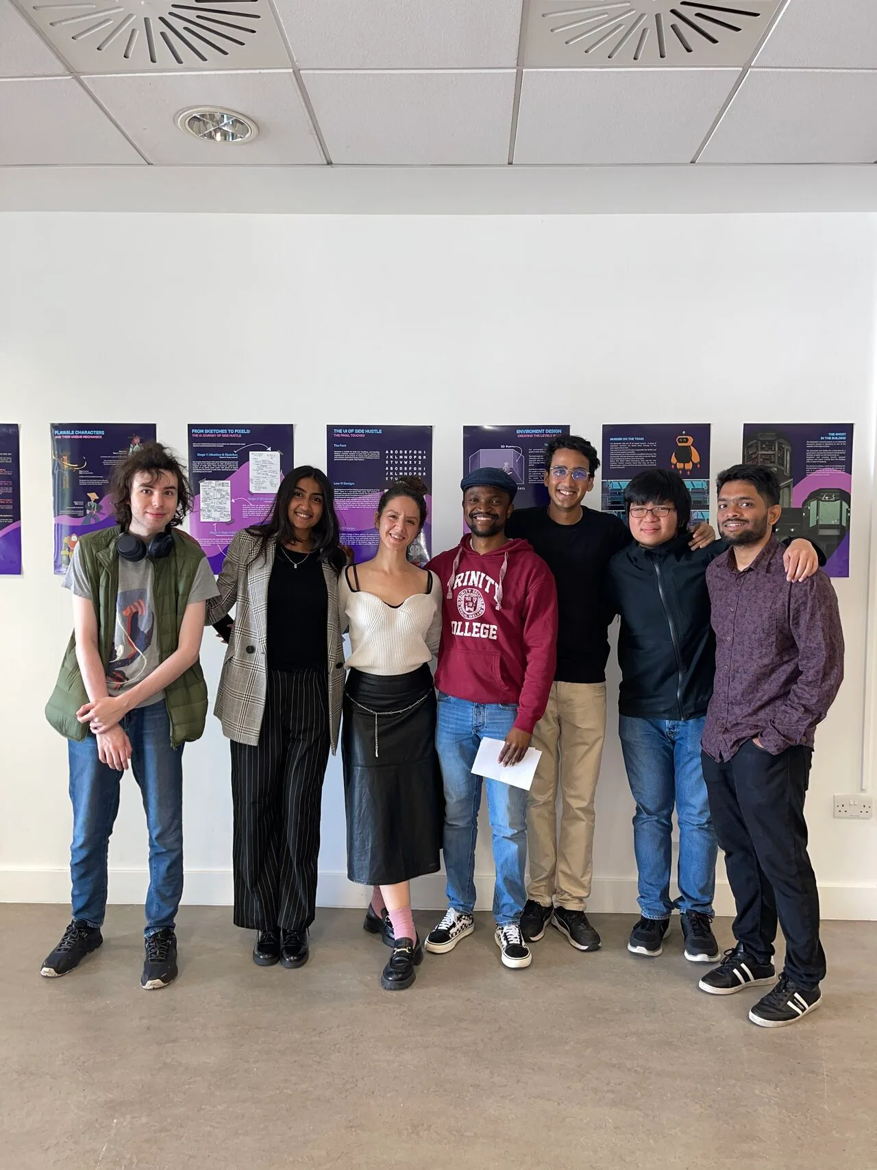 The six-person team standing in front of the Side Hustle posters at the Master's showcase